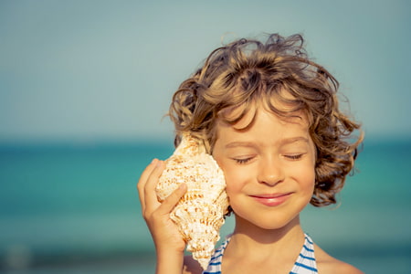 Une fille écoute un coquillage et imagine des histoires